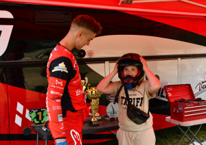 Motosportists palīdz bērnam uzmērīt ķiveri