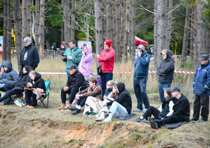 Atbalstītāji sēž kalna galiņā un vēro sportistus