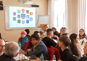 Projekta dalībnieki skatās prezentāciju