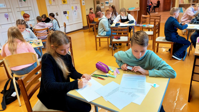 Skolēni pilda uzdevumus pie galdiem