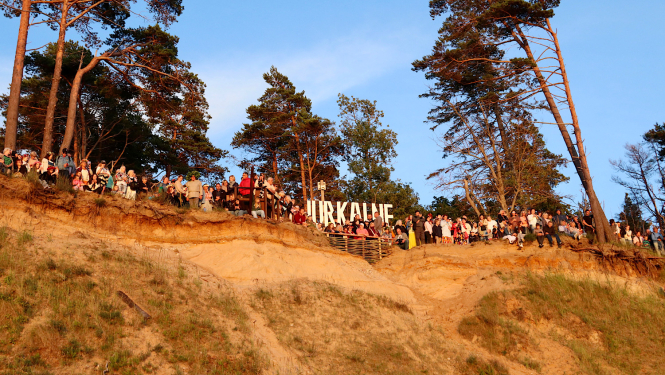 Pasākuma apmeklētāji pie Jūrkalnes burtiem saulrietā