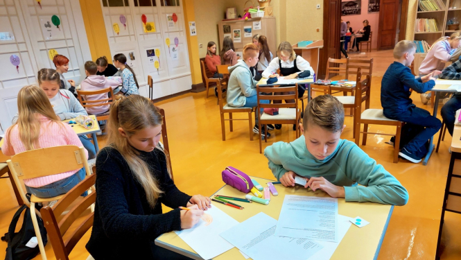 Skolēni pilda uzdevumus pie galdiem