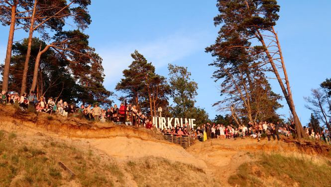 Pasākuma apmeklētāji pie Jūrkalnes burtiem saulrietā