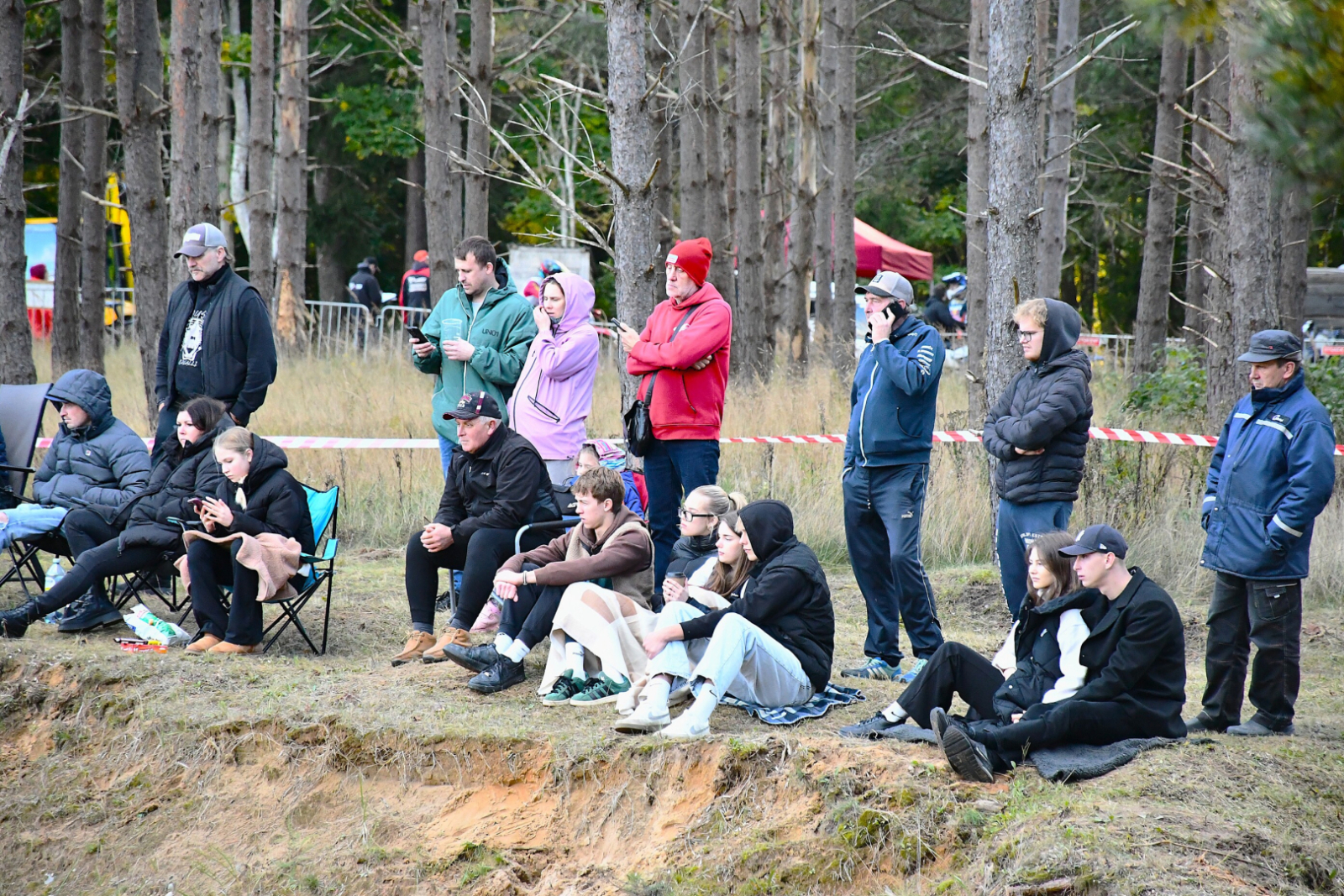 Atbalstītāji sēž kalna galiņā un vēro sportistus