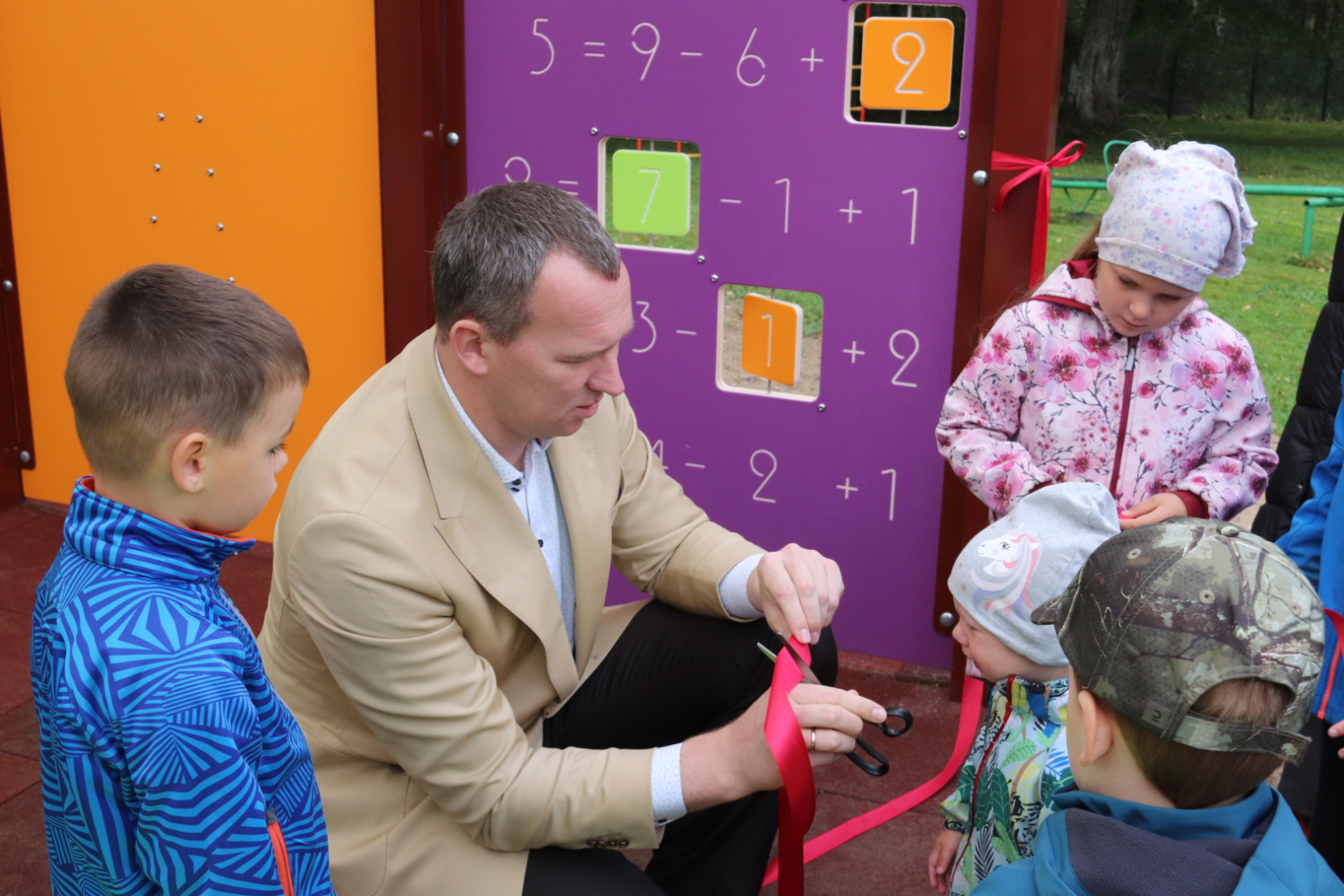 Priekšsēdētājs ar bērniem kopīgi pārgriež lenti un atklāj nojumi