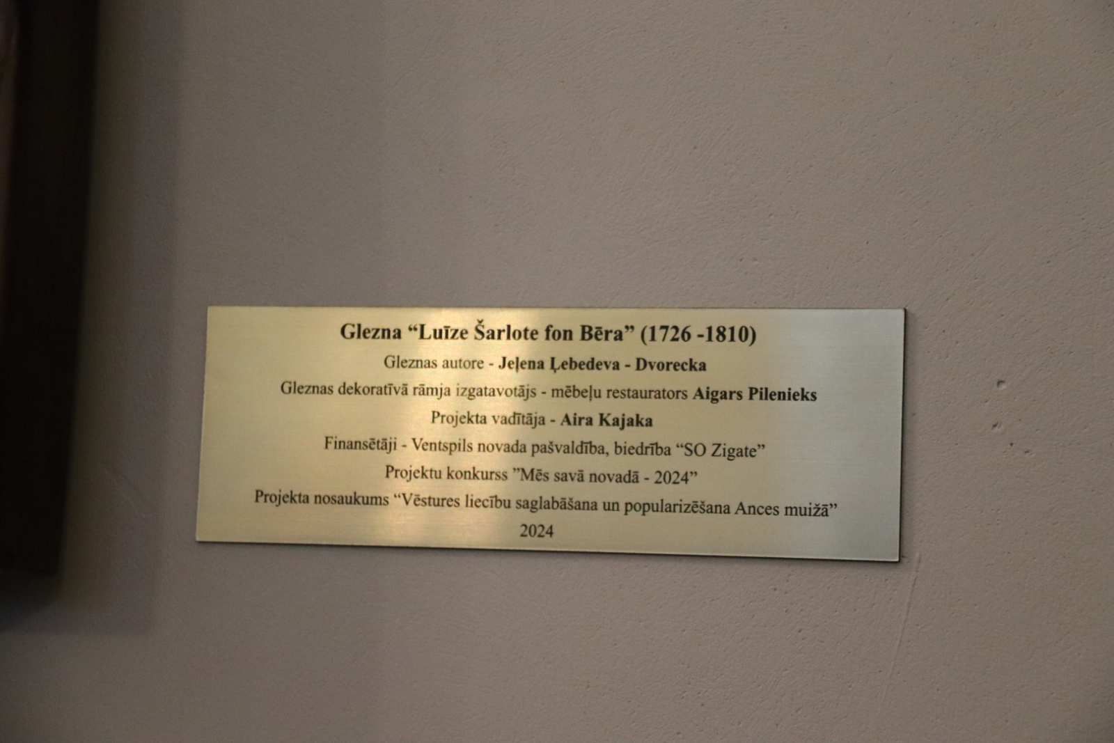 Proti, dekoratīvā ozolkoka rāmī ietērpta ancenieces Jeļenas Ļebedevas-Dvoreckas glezna. “Luīze Šarlote fon Bēra”. 